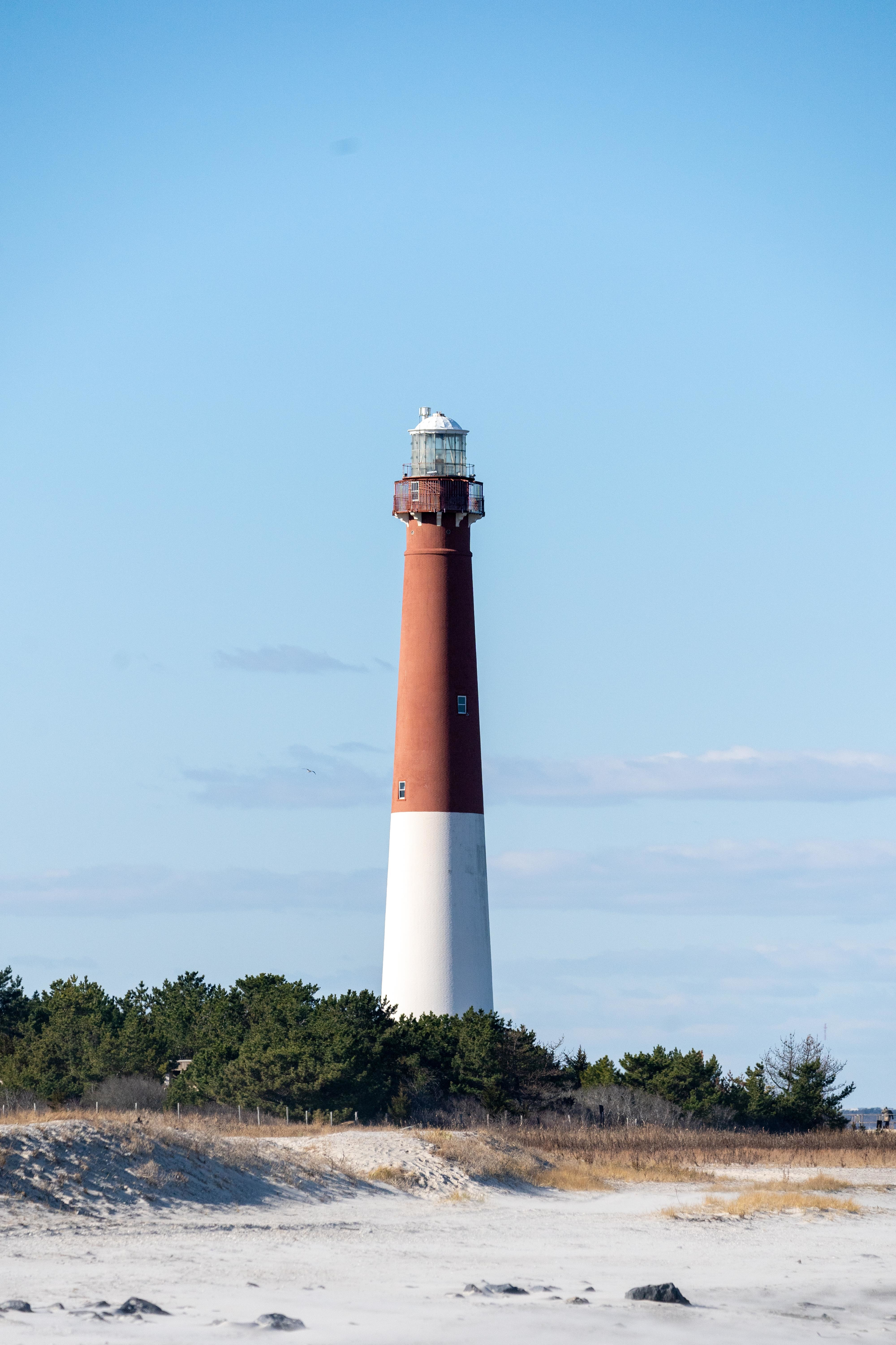 A beautiful lighthouse standing tall on the shore against a blue sky, symbolizing hope and guidance.